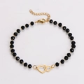 Dettaglio del bracciale a catena dorata con perline nere e ciondolo a doppio cuore - Stile Doppio Cuore
