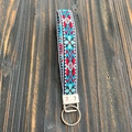 Porte-clés artisanal ethnique en tissu brodé avec motif vintage sur fond de bois sombre - Géométrique Croix Bleu Blanc