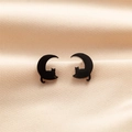 Gros plan de boucles d'oreilles chat et lune noir mat sur fond de soie champagne - Noir