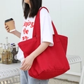 Red large capacity canvas tote bag with shoulder strap shown in a casual outdoor setting - Red