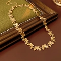 Nahaufnahme der goldenen Schmetterlingskette auf einem Vintage-Rahmen und Stoff - Gold