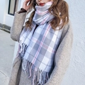 Pink and grey plaid scarf with fringes worn by a model against a white wall background - Fresh Grey White