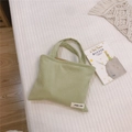 Détail d'un mini sac à main en velours côtelé vert clair avec étiquette tissée - Vert Haricot