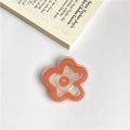 Orange flower phone socket grip holder made of clear acrylic on a white desktop - Orange