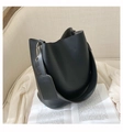 Vue détaillée du sac seau en cuir noir mat avec large bandoulière sur un fond minimaliste chic - Noir