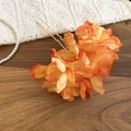 Detailed close-up of an orange fabric flower hair pin with a golden U-shaped metal base - Orange