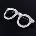 Dettaglio della spilla a forma di occhiali argento con strass su sfondo nero lucido - Argento