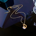 Macro-opname van gouden D-letter hanger ketting met grote zirkoon op zwart reflecterend vlak - Titaniumstaal / Goud