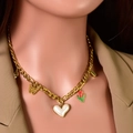 Collier doré avec pendentifs cœur, papillon et tulipe sur un blazer beige élégant - Perle Cœur