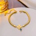 Gold snake chain bracelet with clover pendant and blue evil eye bead on white stand - Gold