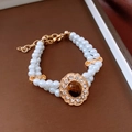 Dettaglio di un braccialetto di perle a due strati con ciondolo a fiore dorato e pietra occhio di tigre - Bracciale (Oro-Bianco)