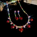 Dettaglio di collana e orecchini a cuore in zircone con pendenti in pietre rosse lucide - Set Multicolore