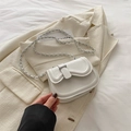 White leather saddle bag with silver chain strap and metal buckle on beige blazer - White