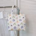 Close-up of a white quilted tote bag featuring colorful cartoon girl prints and logo - Cute Girl