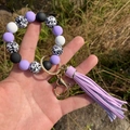 Detailed shot of silicone beaded keychain bracelet with purple tassel and leopard beads - Purple