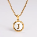 Detail shot of golden necklace with a white shell pendant and embossed letter J inlay - Letter J