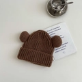Detail of a brown ribbed knit winter hat with double pom-poms for kids, warm texture focus - 3-8 Years / Coffee