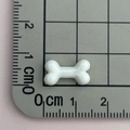 Primo piano di un ciondolo in resina a forma di osso bianco da 1,5 cm su tappetino - Osso Bianco / Bianco