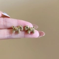 Boucles d'oreilles chiot floquées marron avec accents dorés tenues à la main sur fond chaud - Style Chiot Floqué (77) / Marron
