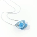 Detailed macro view of an irregular blue raw crystal pendant with a thin silver chain - Apatite
