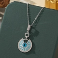 Collier argenté avec œil bleu en émail et strass pavés sur un support vert foncé - A21-argent