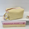 Striped fabric tissue bag with colorful wooden bead chain handle on a white shelf - Yellow