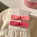 Dettaglio di due fermagli per capelli a fiocco rosa opaco su supporto di carta bianco - D-059 Coppia di Fiocchi Rosa per Ragazza