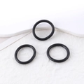 Tre braccialetti minimalisti neri opachi a cerchio su uno sfondo bianco strutturato - Set di 3 anelli neri in gomma (50014 (Anello))