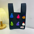 Black knit tote bag with colorful mini hat ornaments and white woven brand label - Colorful Hat With Black Background