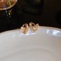 Macro detail of gold plated heart stud earrings featuring sparkling cubic zirconia stones - Gold