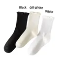 Women's ruffled crew socks in classic black, cream, and white knit fabric - White