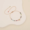 Detailed view of woven crystal bead bracelet with gold heart pendant on wave display - Colorful