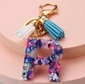 Detail of letter R resin keychain with colorful stones and blue white tassels - Letter R