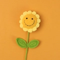 Handmade knitted sunflower with smiling face expression on a vibrant orange background - 7-ring Smiley Face Sunflower Bouquet - Yellow
