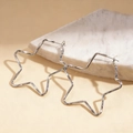 Close-up of minimalist silver star-shaped metal earrings on a white marble surface - Hoop Earrings - Silver / Silver