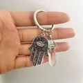 Macro view of Hamsa Hand pendant with evil eye and hexagonal quartz crystal keychain - Clear White