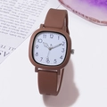 Detail of square vintage watch with brown silicone strap on a minimalist white table - Coffee