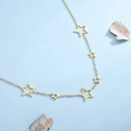 Élégant collier doré avec pendentifs étoiles ajourées sur un fond bleu clair épuré - Doré