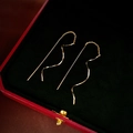 Detail van gouden golfketting oorbellen op een zwart fluwelen sieraden display - Gouden golfketting oor draden