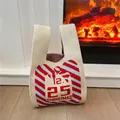Close-up of Christmas knit tote bag with 12.25 patterns in a cozy fireplace setting - Beige Christmas Calendar