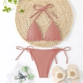 Flat lay of pink ribbed triangle bikini with neck tie and side-tie bottoms on straw mat - Pink
