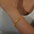 Eleganter vergoldeter Weizenähren-Armreif mit Blattstruktur am Handgelenk einer Frau - Gold