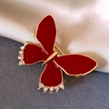 Détail macro d'une broche nœud en émail rouge avec bords dorés et strass blancs brillants - Style Émail Noeud Rouge (33#)