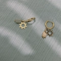 Detailopname van gouden zonne-oorbellen met natuursteen op grijze stoffen achtergrond - Zon Stijl