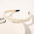 Detailed view of woven white pearls on a gold metal headband with comfortable ends - Braided Large Pearls
