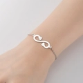 Polished stainless steel infinity bracelet with double heart charms on a delicate chain - Infinity Steel Color
