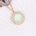 Close-up of sunburst pendant with green enamel smiley face and sparkling cubic zirconia - Green