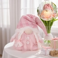 Pink glowing Christmas gnome ornament with sequins and white braids on a table - Female Glowing Gnome Ornament
