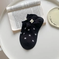 Black cotton low cut star socks with white star patterns and green mini label on white plate - One Size / Black