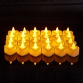 Set of 24 heart-shaped LED tea lights with warm yellow flame on reflective black background - Heart Electronic Candle